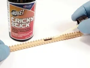 Aplicarea Deluxe Materials Tricky Stick cu pensula pe o senilă de plastic la un model RC, demonstrând amorsarea suprafeței înainte de lipirea cu adeziv cianoacrilat