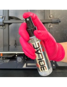 O mână utilizează vaporizatorul pentru a aplica adezivul lichid 3D Lac Plus direct pe patul încălzit al unei imprimante 3D, asigurând aderența optimă.