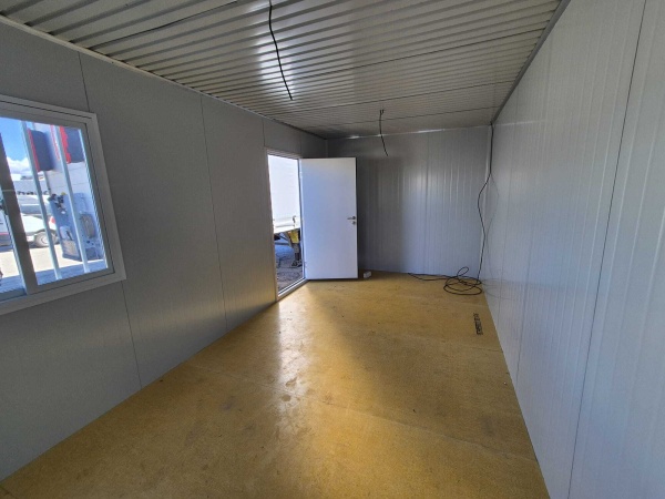 Interior de container cu ferestre, ușă deschisă și cablu electric pe podea