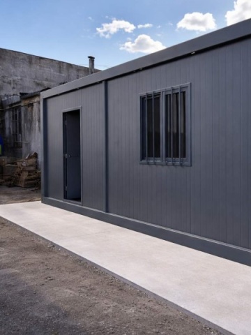 Container gri închis cu ușă și fereastră cu grilaj, fotografiat pe platformă