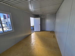 Interior de container cu ferestre, ușă deschisă și cablu electric pe podea