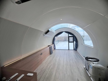 Interior luminos al capsulei, văzut spre ușa cu geam curbat