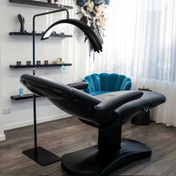 Lampă semilună poziționată deasupra unui pat cosmetic negru