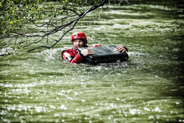 Alpinist ținut la suprafața unui râu de geanta de protecție Peli Air Case 1555 