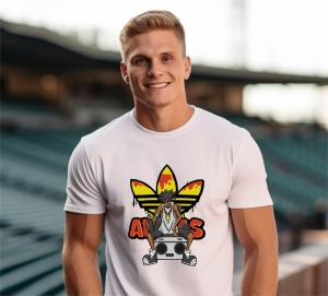 Bărbat purtând un tricou alb cu un design colorat, reprezentând un personaj urban așezat pe o boxă portabilă, încadrat de un logo reinterpretat cu culori galben și roșu, fotografiat pe un fundal de stadion.