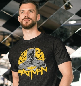Bărbat purtând un tricou negru cu un design al personajului Batman, având un fundal galben cu lilieci și textul 'BATMAN' dedesubt. Fundalul este un decor modern cu oglinzi și linii diagonale.
