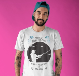 Imagine cu un bărbat purtând un tricou alb pe care este imprimat un design cu mesajul 'Cei mai buni pescari sunt născuți în martie', cu o siluetă de pescar și ilustrații de pești.