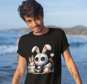 Tânăr zâmbitor purtând un tricou negru cu un design festiv care îl înfățișează pe Jack Skellington cu urechi de iepuraș de Paște, alături de un iepuraș și un coș cu ouă colorate. Fundalul este o plajă cu mare și munți în depărtare.
