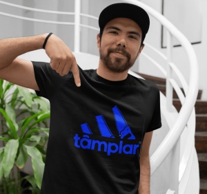 Un bărbat poartă un tricou negru cu un design amuzant inspirat de un logo faimos, prezentând trei dungi stilizate ca fierăstraie și textul 'tâmplar' dedesubt. Bărbatul poartă o șapcă și arată cu degetul spre designul de pe tricou. Fundalul include o scară