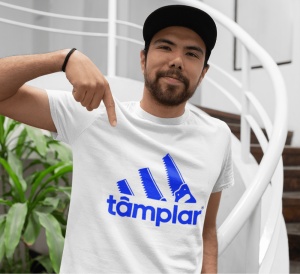 Un bărbat poartă un tricou alb cu un design amuzant inspirat de un logo faimos, prezentând trei dungi stilizate ca fierăstraie și textul 'tâmplar' dedesubt. Bărbatul poartă o șapcă și arată cu degetul spre designul de pe tricou. Fundalul include o scară i