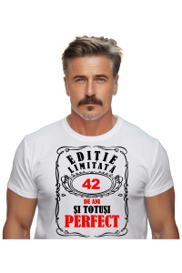 Un bărbat purtând un tricou alb cu mesajul: „Ediție limitată, 42 de ani și totuși perfect”. Bărbatul afișează o atitudine veselă și pozitivă.