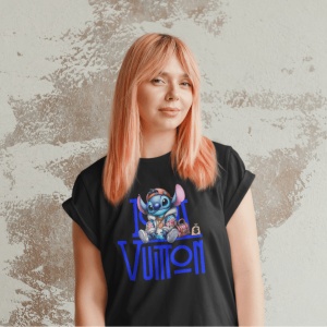 Femeie cu păr roz purtând un tricou negru cu un design grafic ce înfățișează un personaj animat(Stitch) și textul 'Louis Vuitton,' pozând în fața unui perete cu textură abstractă.