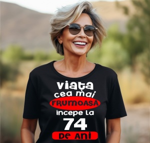 Femeie care poartă un tricou negru personalizat cu mesajul: ''Viata cea mai frumoasa incepe la 74 de ani''.