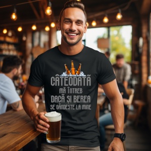 Un bărbat zâmbitor într-un bar, purtând un tricou negru cu textul umoristic: "CÂTEODATĂ MĂ ÎNTREB DACĂ ȘI BEREA SE GÂNDEȘTE LA MINE", ilustrat cu trei sticle de bere într-un strat de gheață. Ține în mână un pahar de bere, iar în fundal se observă o atmosf