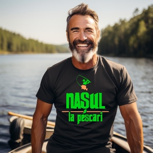 Un bărbat zâmbitor cu barbă purtând un tricou negru cu text imprimat "Nașul la pescari" în culori verzi și portocalii, având un logo cu o undiță stilizată și aflându-se într-o barcă pe un lac înconjurat de pădure.