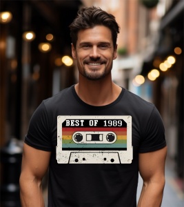 Un bărbat zâmbitor purtând un tricou negru cu o imagine stilizată a unei casete audio și textul ''Best of 1989''.