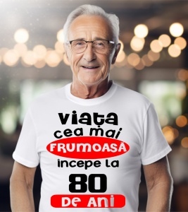 Un bărbat purtând un tricou alb cu textul ''Viața cea mai frumoasă începe la 80 de ani''.