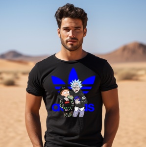 Bărbat purtând un tricou negru cu logo Adidas albastru și un design cu personaje animate, pozând într-un peisaj deșertic.