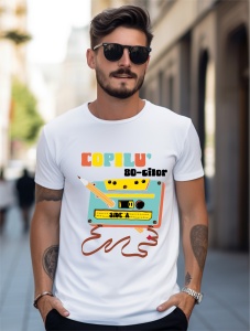 Un bărbat purtând un tricou alb cu un design nostalgic inspirat de anii '80, ce prezintă o casetă audio și un creion, alături de textul 'Copilu' 80-tilor', evocând amintiri din copilăria acelei perioade.