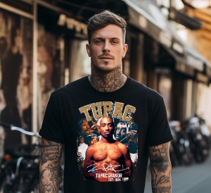Bărbat cu tatuaje, purtând un tricou negru cu imaginea lui Tupac Shakur și textul „Tupac 1971-1996”. Fundalul este urban, cu un decor de stradă și biciclete în spate.