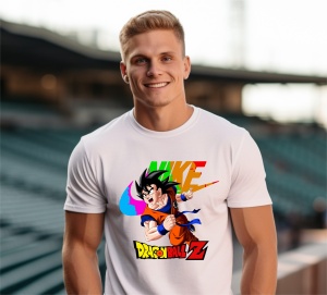 Bărbat zâmbitor purtând un tricou alb cu un design colorat ce include un personaj din Dragon Ball Z și un logo reinterpretat în culori vii, pozând într-un cadru exterior pe un stadion.