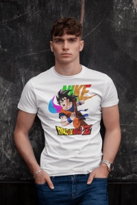 Tânăr purtând un tricou alb cu un design colorat ce include un personaj din Dragon Ball Z și un logo reinterpretat în culori vibrante, pozând relaxat în fața unui perete gri închis.