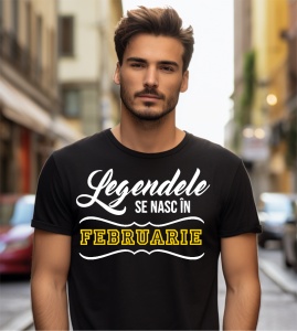 Un tânăr cu barbă, purtând un tricou negru cu mesajul: „Legendele se nasc în Februarie”. Bărbatul se află pe o stradă urbană, cu clădiri în fundal.