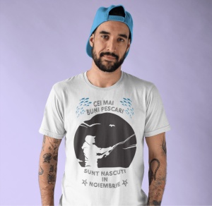 Imagine cu un bărbat purtând un tricou alb pe care este imprimat un design cu mesajul 'Cei mai buni pescari sunt născuți în noiembrie', cu o siluetă de pescar și ilustrații de pești.