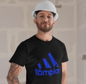 Un bărbat purtând o cască de protecție albă și un tricou negru cu un design amuzant inspirat de un logo faimos, ce afișează trei dungi stilizate ca fierăstraie și textul 'tâmplar' scris dedesubt. Fundalul sugerează un spațiu de construcție sau renovare.