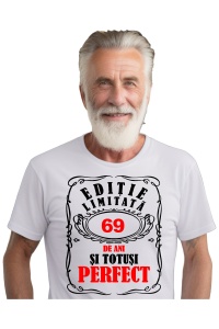 Un bărbat purtând un tricou alb cu mesajul: „Ediție limitată, 69 de ani și totuși perfect”. Bărbatul afișează o atitudine veselă și pozitivă.