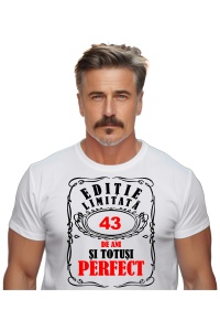 Un bărbat purtând un tricou alb cu mesajul: „Ediție limitată, 43 de ani și totuși perfect”. Bărbatul afișează o atitudine veselă și pozitivă.