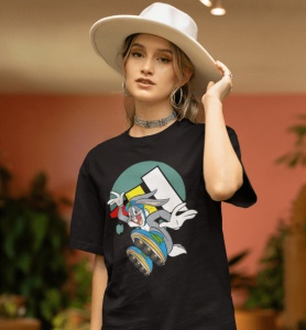 Femeie purtând un tricou negru cu un design grafic colorat cu un personaj din desene animate pe role(Bugs Bunny), combinat cu pantaloni scurți de denim și o pălărie albă, pozând într-un spațiu interior decorat cu plante.