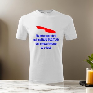Tricou alb cu un mesaj tipografic albastru care spune 'Nu este ușor să fii cel mai bun bucătar, dar cineva trebuie să o facă', decorat cu o iconiță roșie în formă de cuțit