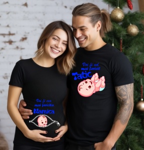Un cuplu zâmbitor purtând tricouri albe personalizate pentru viitori părinți. Tricoul bărbatului are mesajul 'Voi fi cel mai fericit Tătic' cu un design de bebeluș zâmbitor, iar tricoul femeii are mesajul 'Voi fi cea mai fericită Mămică' cu un design de f