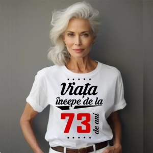 Femeie care poartă un tricou alb personalizat cu mesajul: ''Viața începe de la 73 de ani''