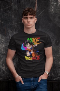 Tânăr purtând un tricou negru cu un design colorat ce include un personaj din Dragon Ball Z și un logo reinterpretat în culori vibrante, pozând relaxat în fața unui perete gri închis.