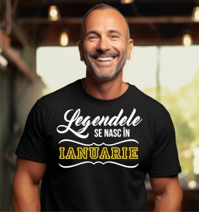 Un bărbat zâmbitor, cu păr scurt, purtând un tricou negru cu mesajul: „Legendele se nasc în Ianuarie”. Bărbatul se află într-un cadru interior, cu lumini în fundal.