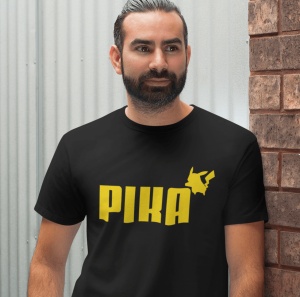 Un bărbat cu barbă poartă un tricou negru cu textul 'PIKA' scris în galben și o siluetă stilizată a unui personaj celebru(Pikachu), plasată deasupra textului.