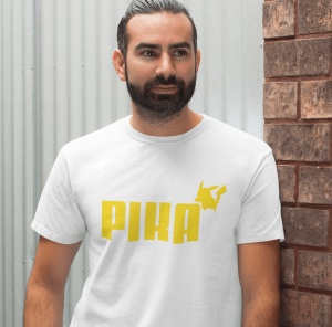 Un bărbat cu barbă poartă un tricou alb cu textul 'PIKA' scris în galben și o siluetă stilizată a unui personaj celebru(Pikachu), plasată deasupra textului.