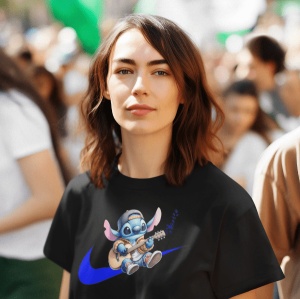 Femeie cu părul șaten și ondulat, purtând un tricou negru cu un design ce ilustrează un personaj animat albastru(Stitch) cântând la chitară, având șapcă, așezat pe logo-ul albastru al unui brand sportiv. Femeia are o expresie calmă și se află într-un cadr