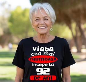 Femeie care poartă un tricou negru personalizat cu mesajul: ''Viata cea mai frumoasa incepe la 92 de ani''.