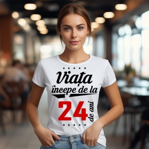 O femeie purtând un tricou alb cu textul  'Viața începe de la 24 de ani'. Fundal din lemn cu diferite nuanțe de maro și verde.