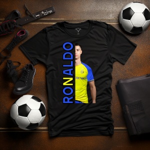 Tricou negru personalizat cu imaginea fotbalistului Ronaldo și text vertical albastru cu numele 'Ronaldo', așezat pe o masă cu mingi de fotbal, ghete și accesorii sportive.