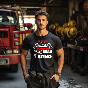 Bărbat tânăr și atletic, îmbrăcat într-un tricou negru personalizat cu textul 'SA-MI ZICI POMPIER, CA BEAU DE STING', ilustrat cu o cască de pompier, două topoare și un pahar de vin. Fundalul prezintă interiorul unei stații de pompieri, cu o mașină de pom