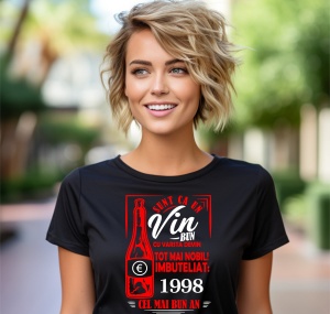 Femeie zâmbitoare purtând un tricou negru cu un mesaj în română despre vin, în care se menționează că este ca un vin bun care devine mai nobil cu vârsta, îmbuteliat în 1998, cel mai bun an.