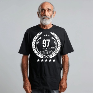 Un bărbat zâmbitor purtând un tricou negru cu textul ''97 de ani de excelență'', înconjurat de o coroană de lauri.