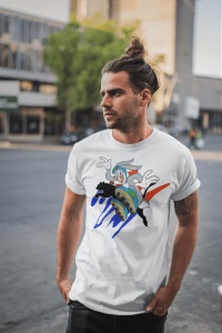 Bărbat cu păr prins în coc, purtând un tricou alb cu un design colorat ce reprezintă un personaj animat într-o scenă dinamică, pozând într-un cadru urban pe o stradă aglomerată.