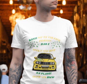 Un bărbat poartă un tricou alb cu un mesaj amuzant în limba română care spune 'Banii nu te vor face fericit, dar e mult mai bine să plângi într-un BMW', însoțit de o ilustrație a unei mașini BMW galbene. Fundalul este iluminat cald, sugerând un interior d