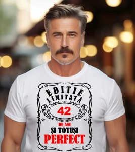 Un bărbat purtând un tricou alb cu mesajul: „Ediție limitată, 42 de ani și totuși perfect”. Bărbatul afișează o atitudine veselă și pozitivă.