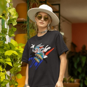 Femeie purtând un tricou negru cu un design grafic colorat cu un personaj din desene animate pe role(Bugs Bunny), accesorizat cu o pălărie albă și ochelari de soare, pozând într-un spațiu interior decorat cu plante verzi și ghivece colorate.